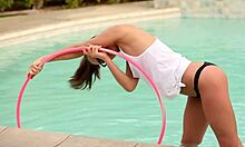 Lasit-yllään poninhäntä teini tyttöystävä poseeraa hula vanteen uima-altaalla